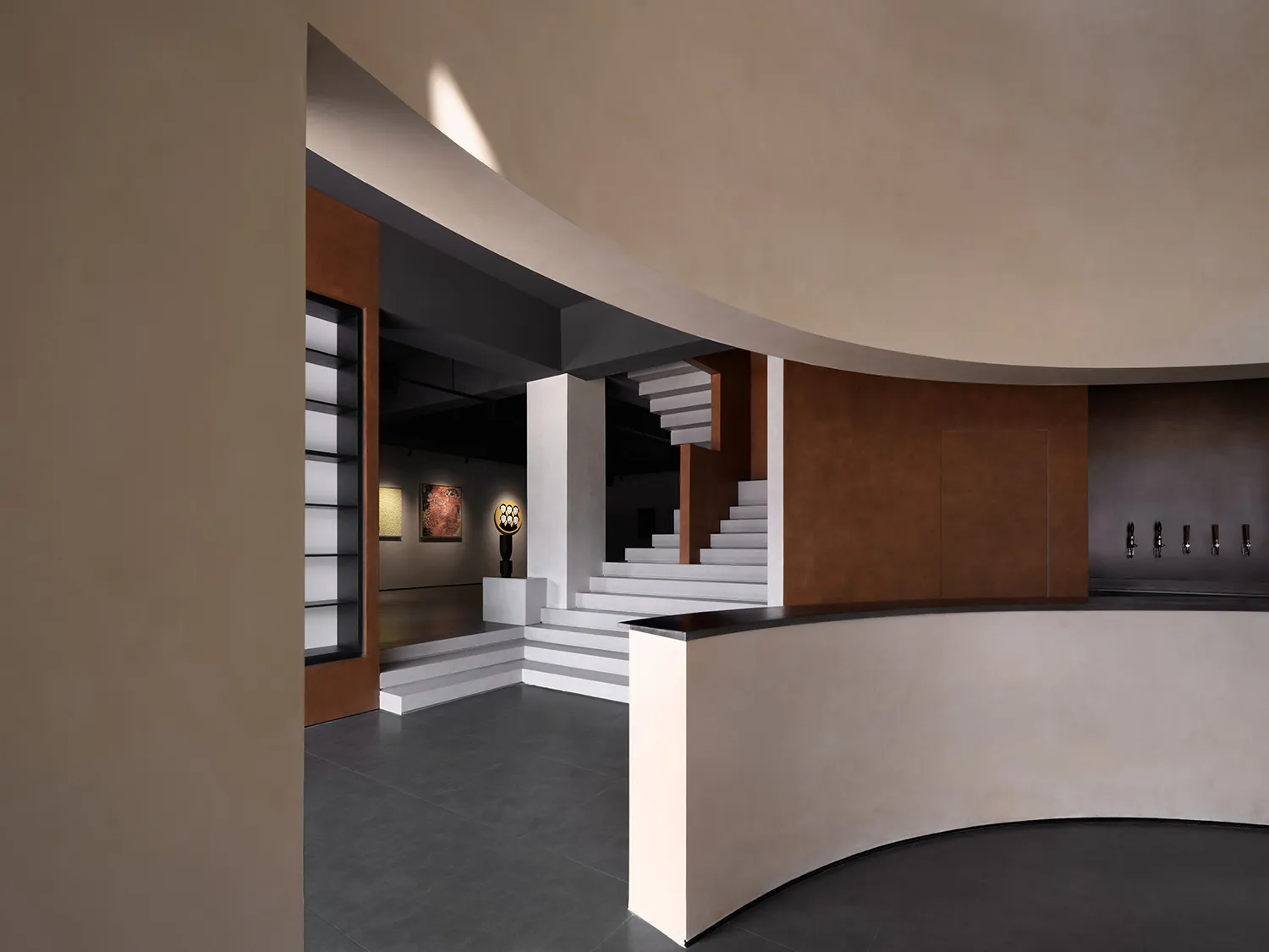 A modern architectural museum with concrete walls and a metal staircase.