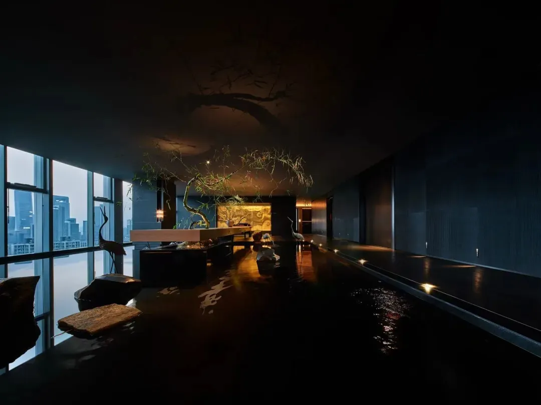 Modern interior featuring an atrium with a glass wall, water feature, and wooden accents.