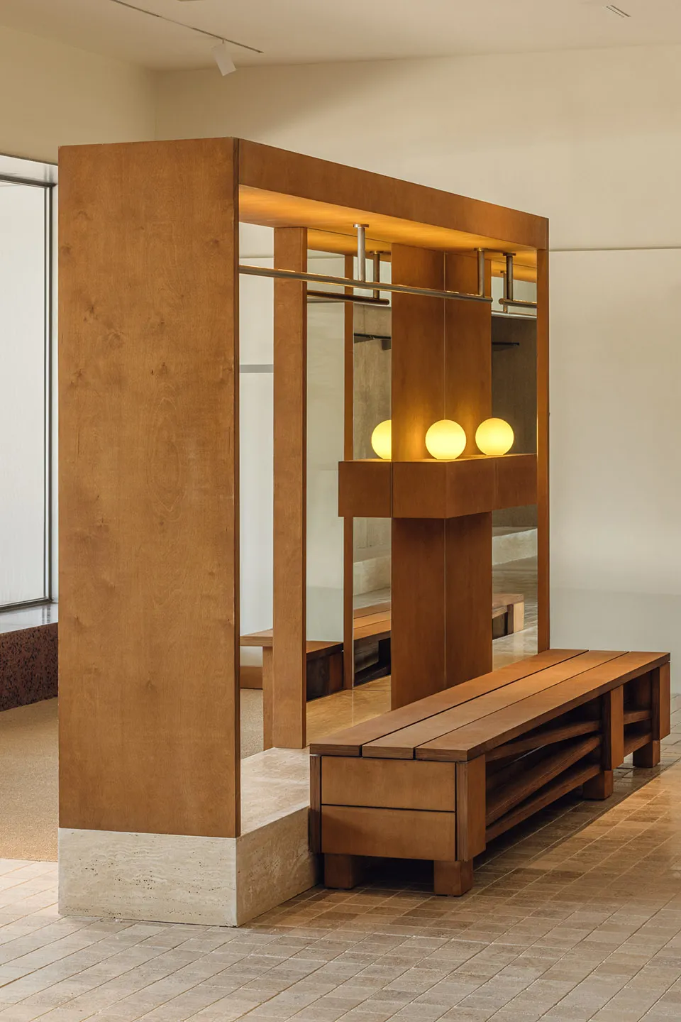 Modern minimalist entryway featuring a wooden bench and mirrored closet