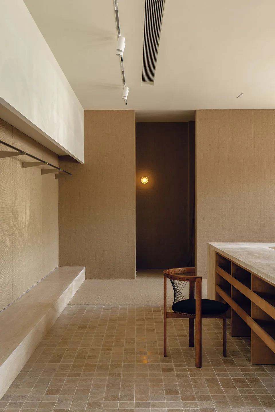 Interior of a minimalist office with concrete walls and floor, featuring a modern chair and desk setup.