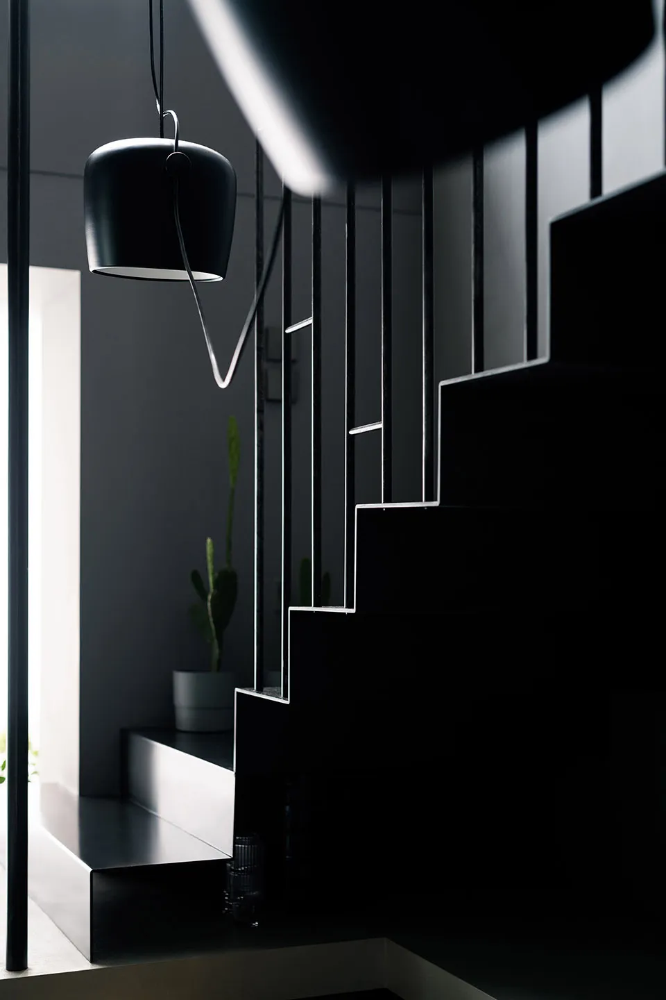 Modern minimalist interior design featuring glass stairs and black elements.
