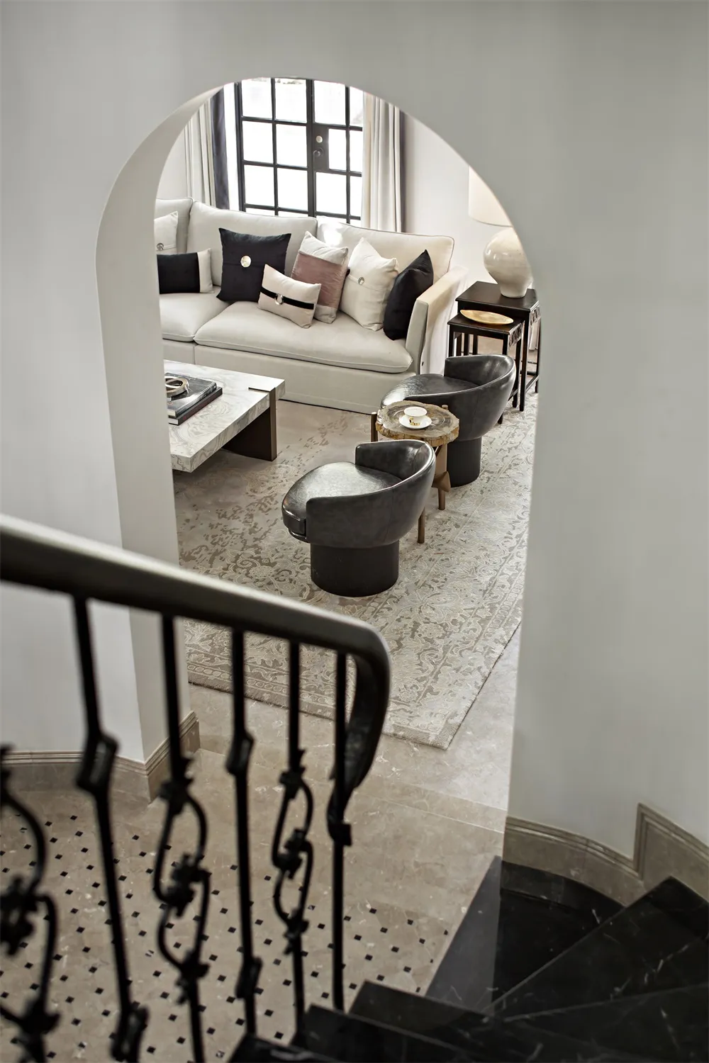 A minimalist living room with marble floors and a concrete fireplace, featuring modern furniture and a large window.