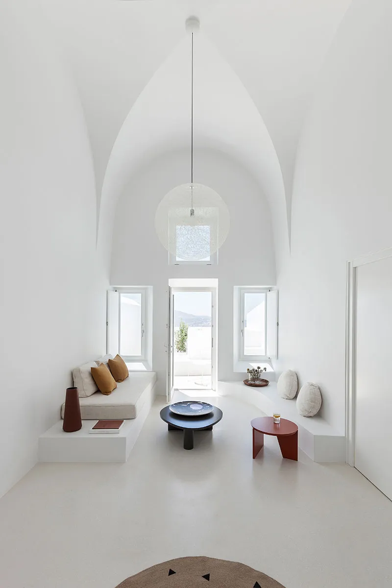 A modern minimalist living room with a white interior, featuring a cozy seating area, a sleek black coffee table, and a large