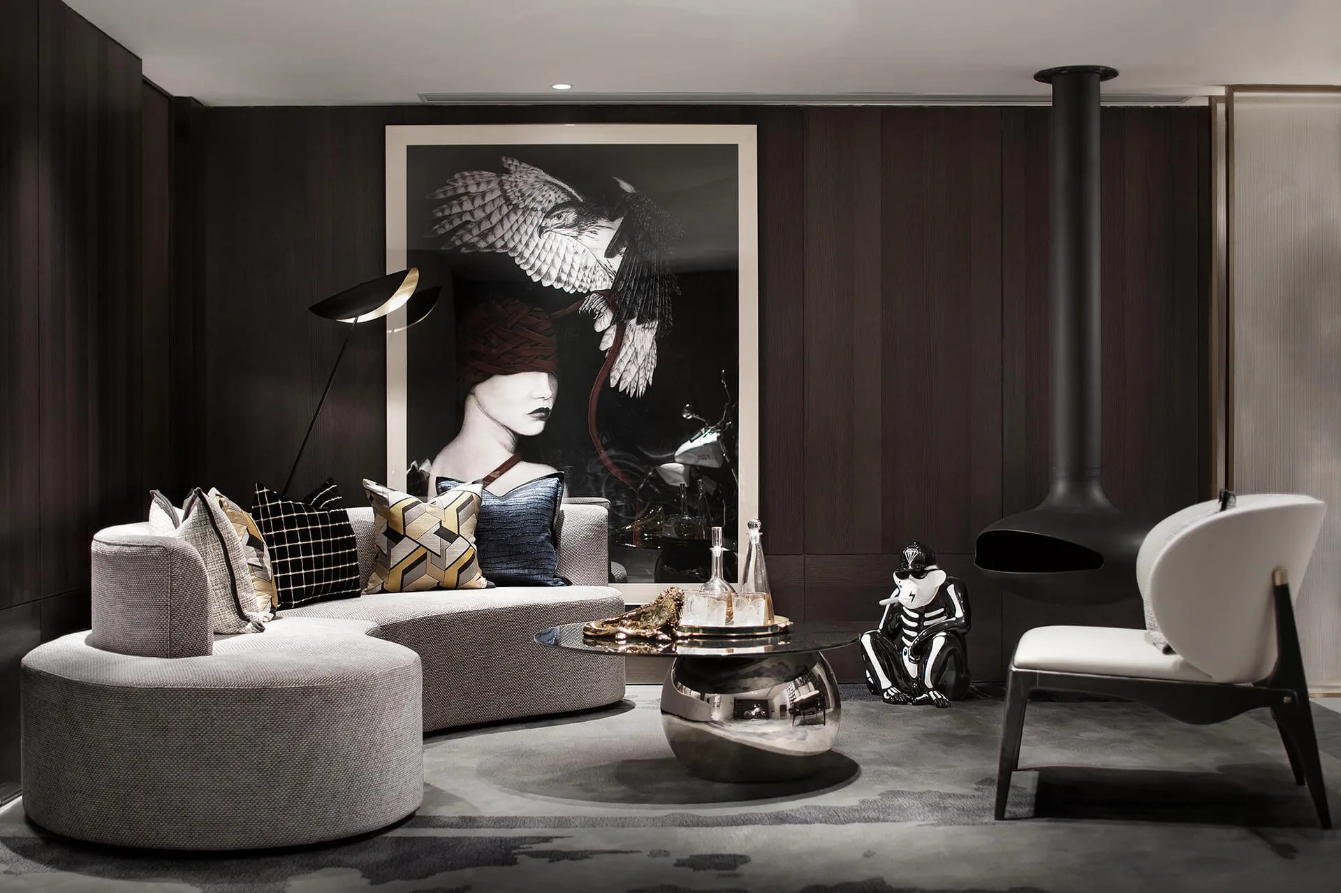 A modern living room featuring a round sofa with patterned pillows, a unique coffee table with a black fireplace and a black