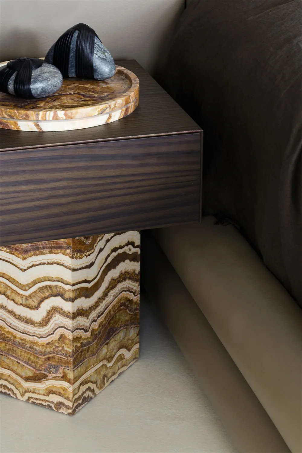 A minimalist bedroom featuring a stone bedside table with a dark wood drawer.