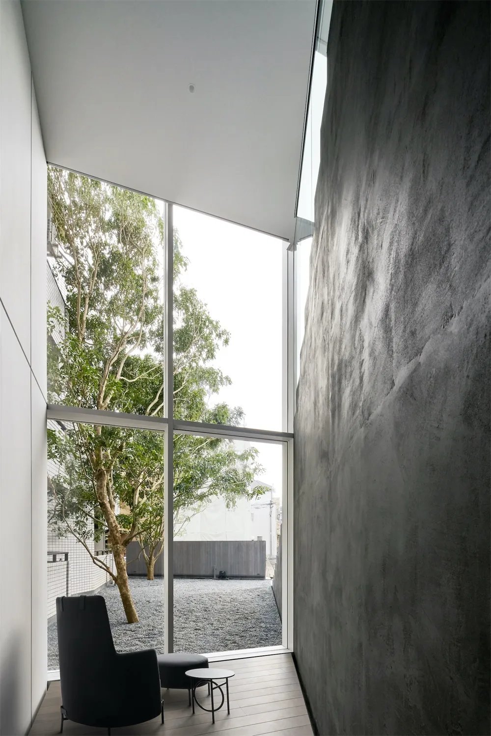 A minimalist residential interior featuring concrete walls and large glass window.