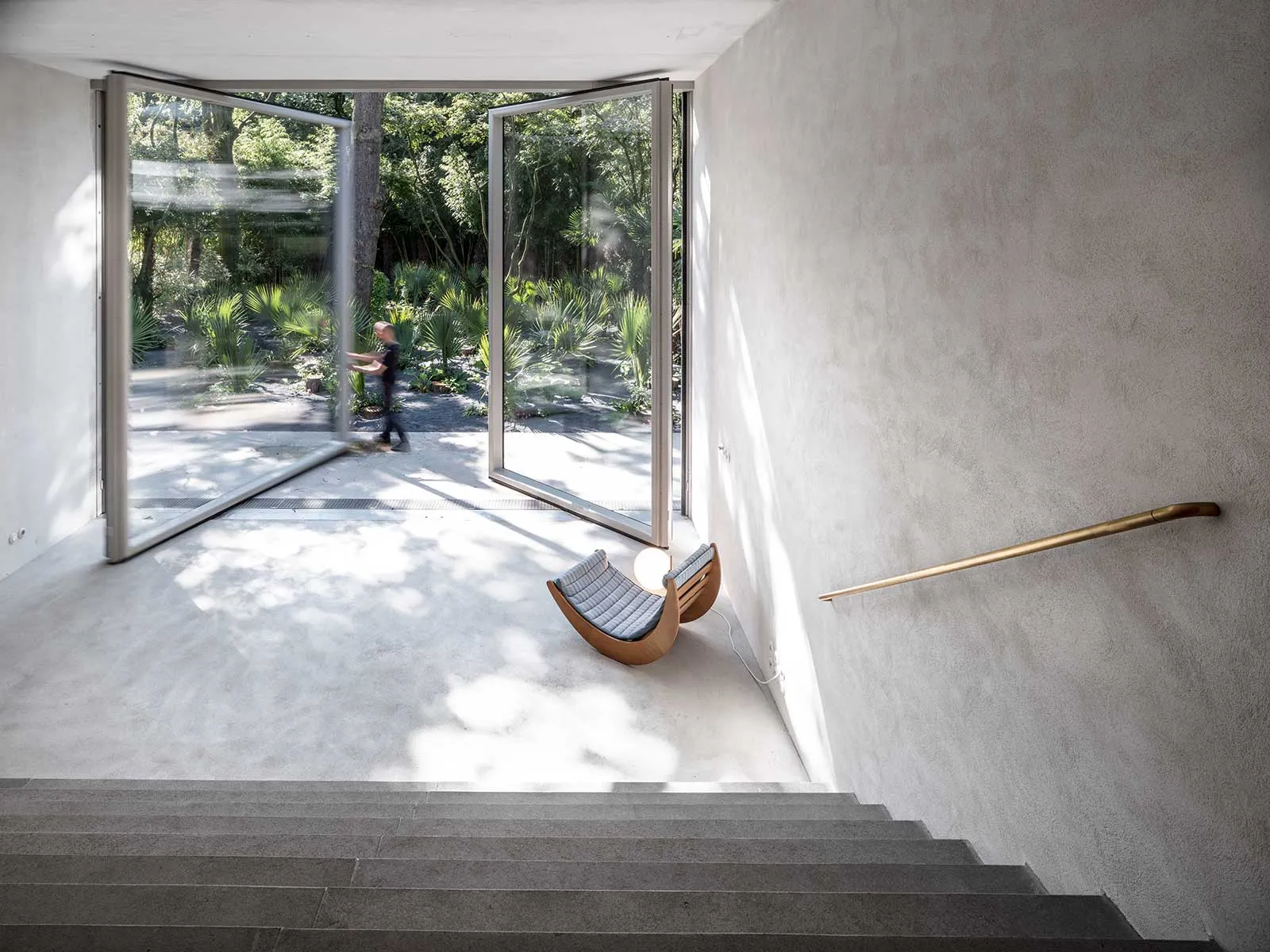 Concrete stairs with a modern, minimalist design, featuring an open-air entrance leading to a garden.