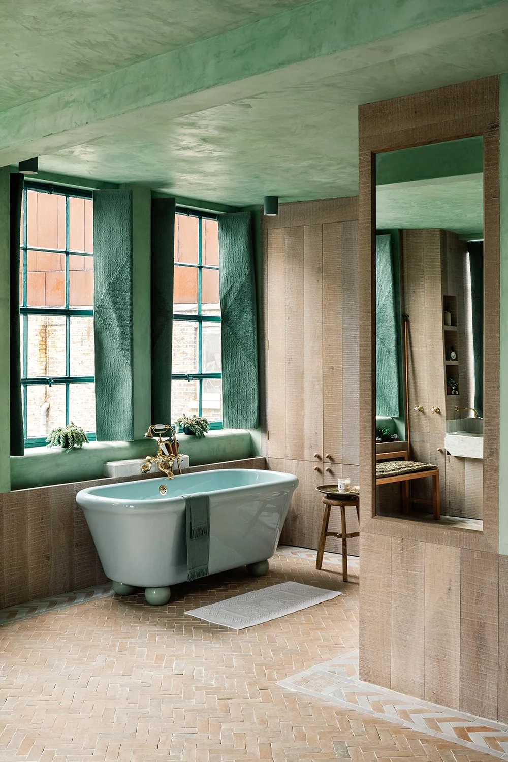 A modern bathroom with wooden walls, green accents, and a freestanding bathtub.