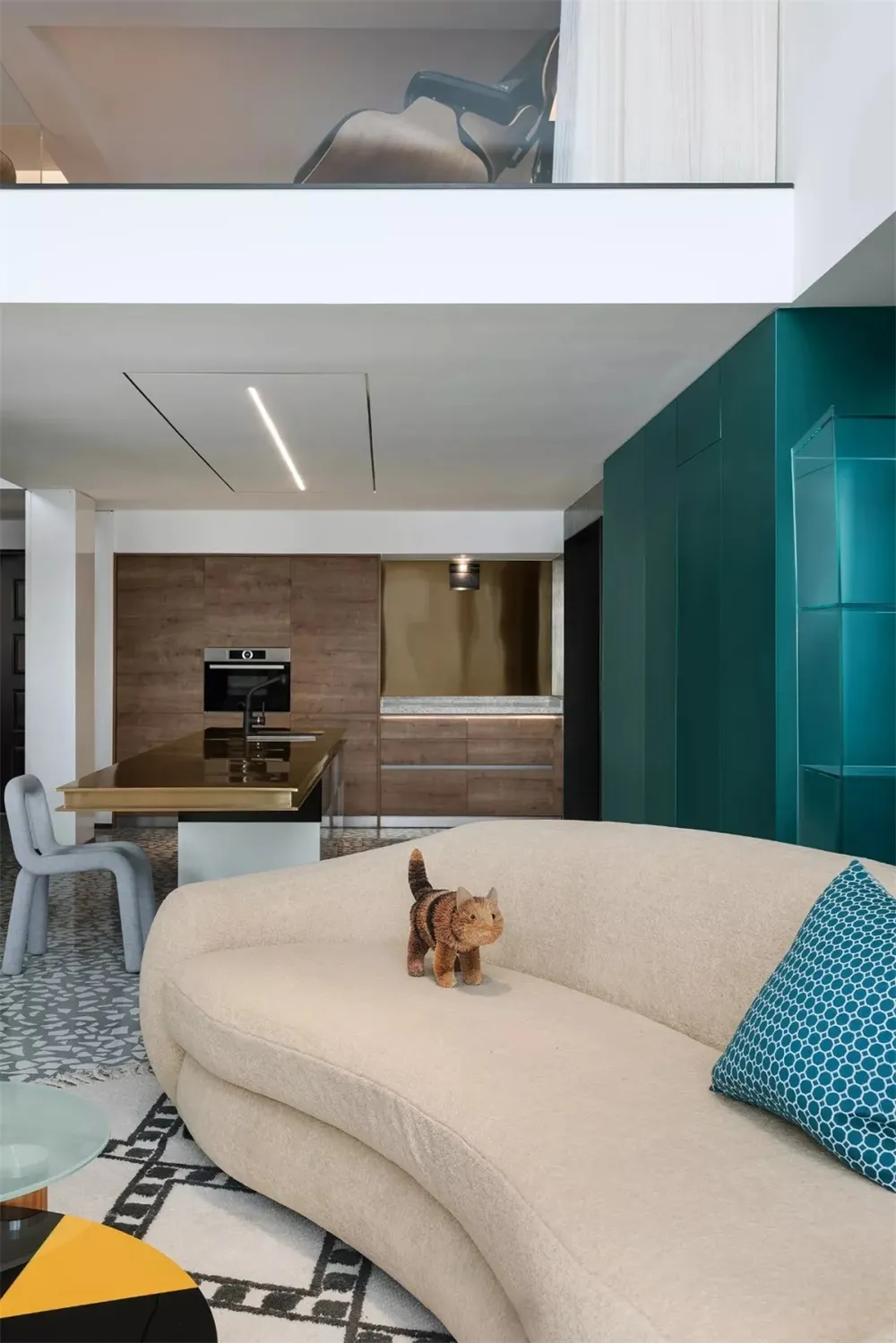 A modern living room featuring a beige curved sofa, blue patterned rug, and a green wall.