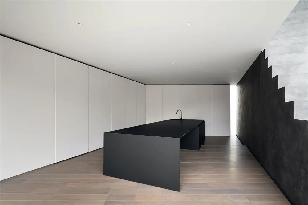 Modern minimalist kitchen with a black island counter and white cabinetry.