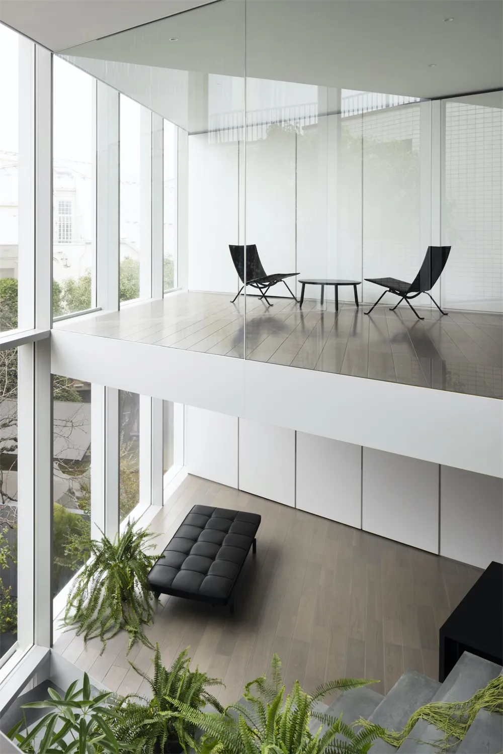 A modern minimalist white interior with glass walls and a rooftop patio.