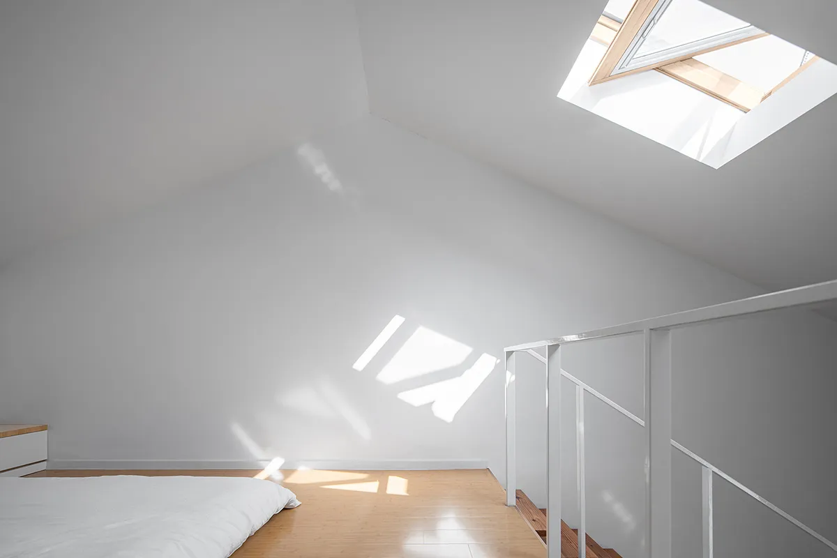 Modern bedroom with a white concrete wall and floor features a bed with a minimalist design.