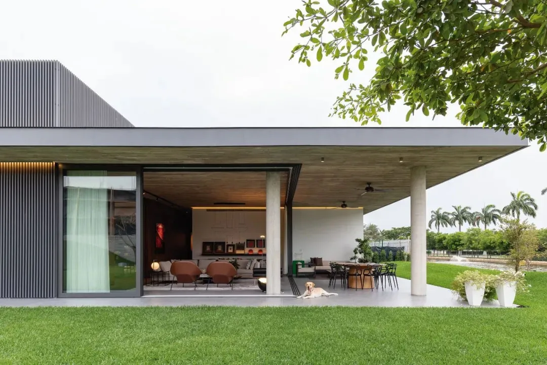 A modern house with a concrete exterior and large glass windows.