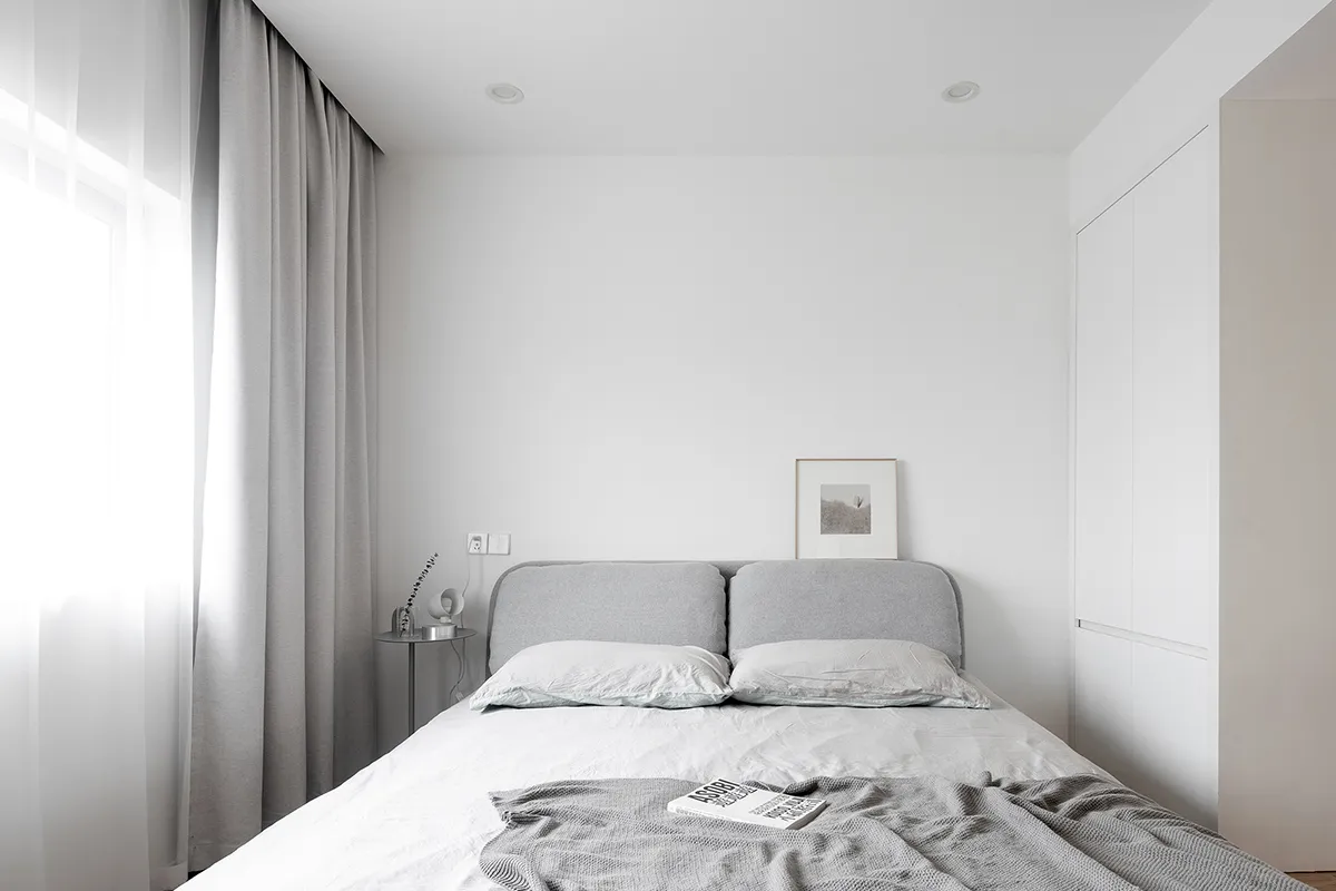 A minimalistic bedroom featuring a bed with soft textiles and a simple, elegant design.