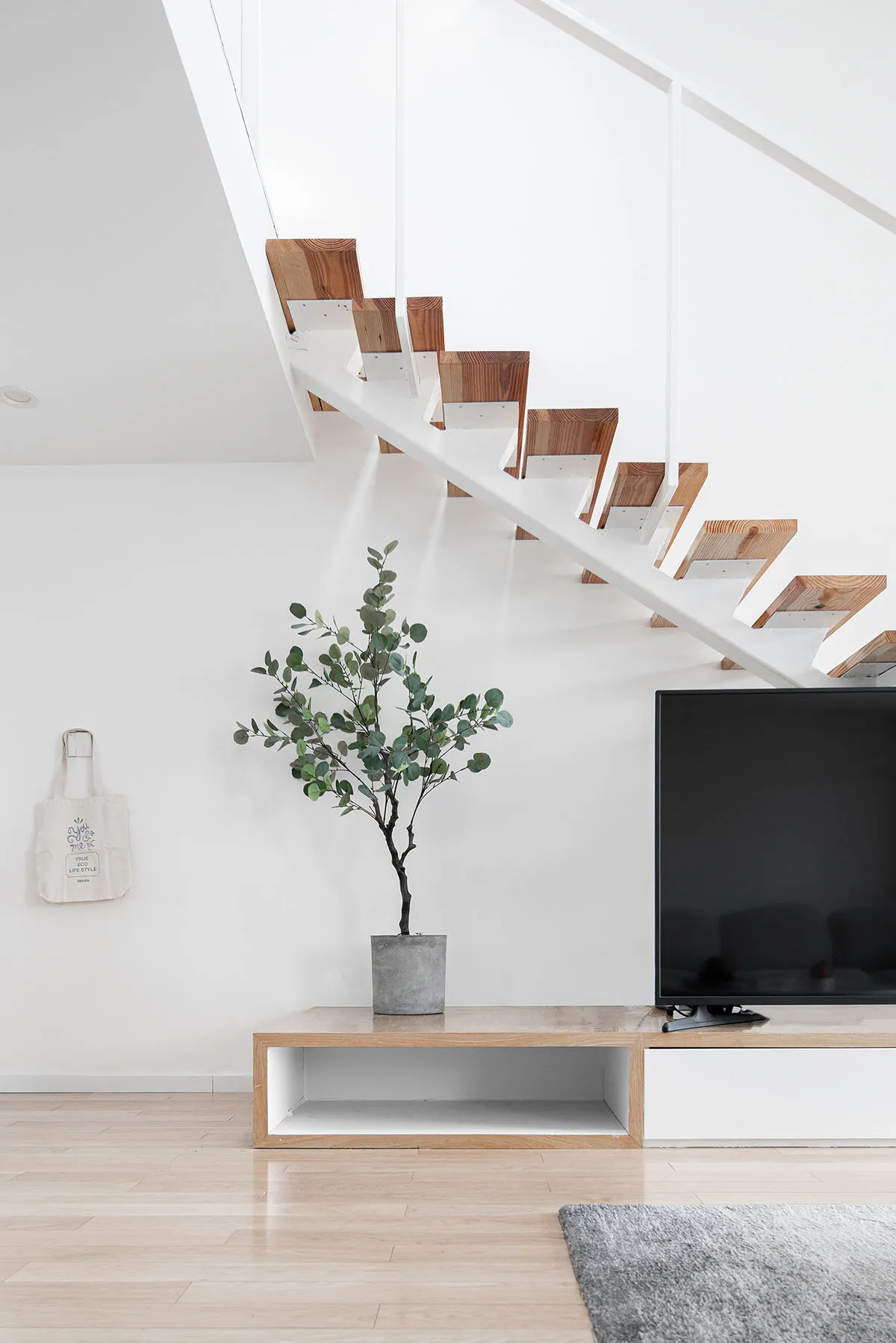 Modern minimalist staircase interior with white walls and wooden stairs.