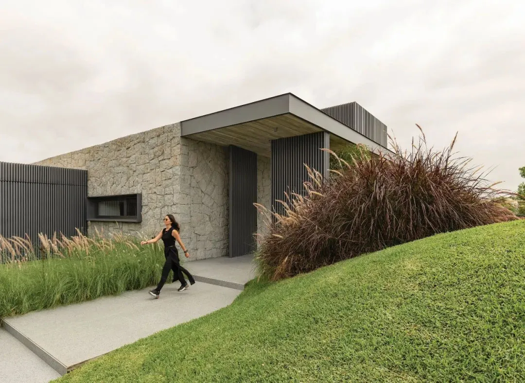 A contemporary residential exterior with stone walls and metal cladding.