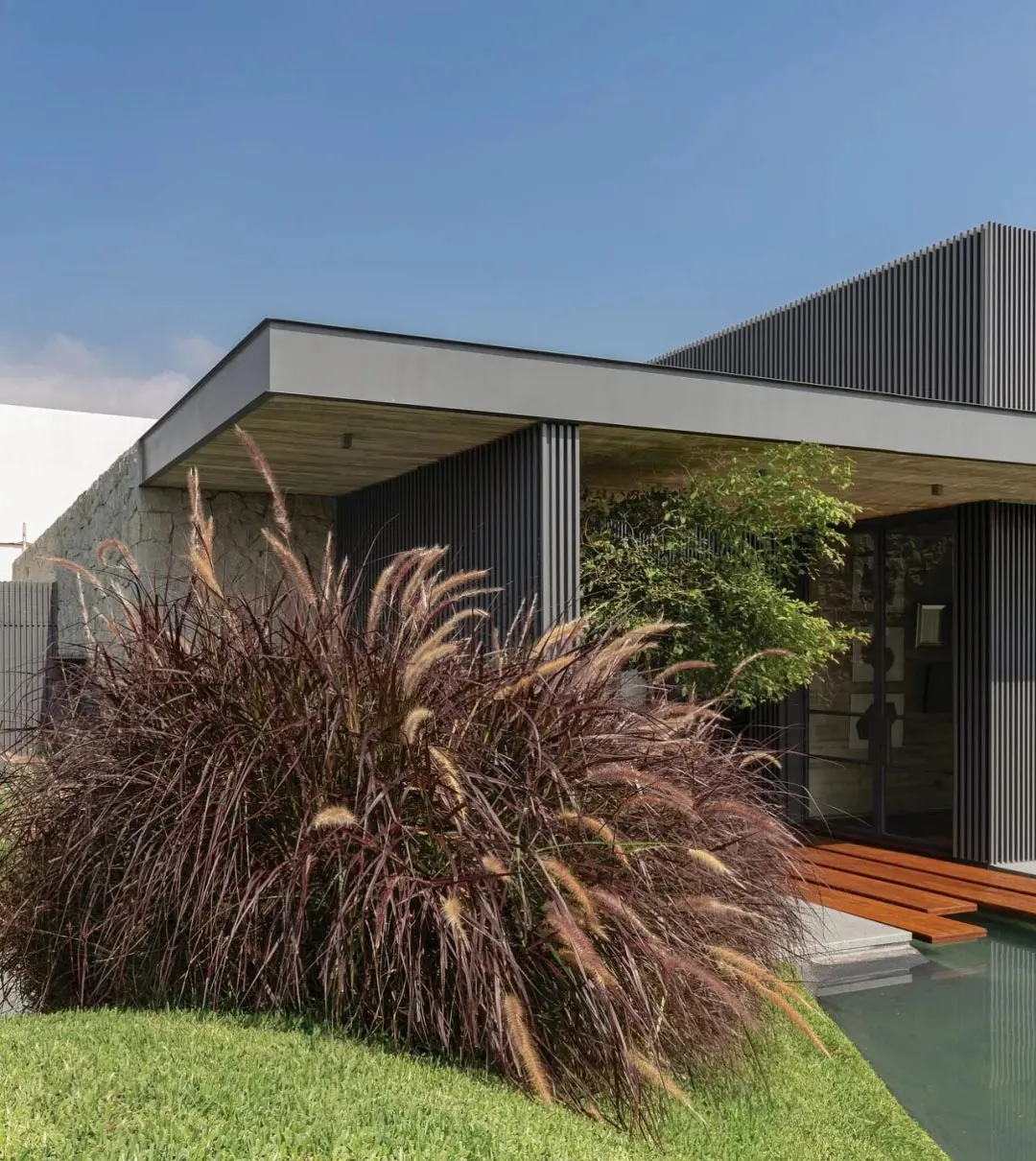 A modern residential exterior featuring metal, stone, and concrete elements.