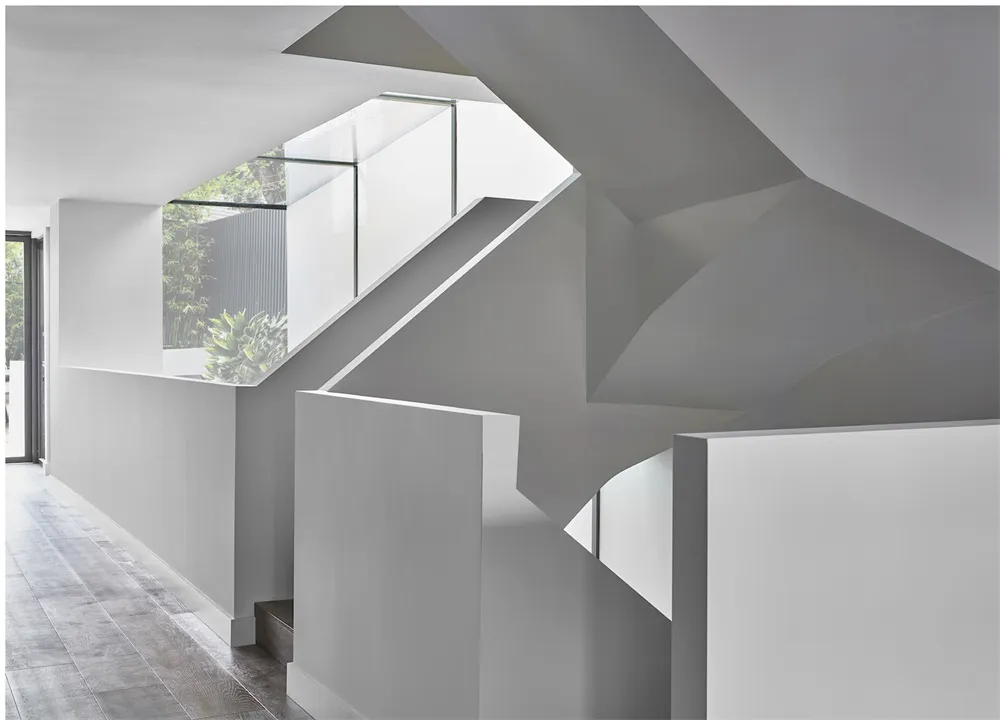 A modern minimalist staircase with white concrete walls and steps.