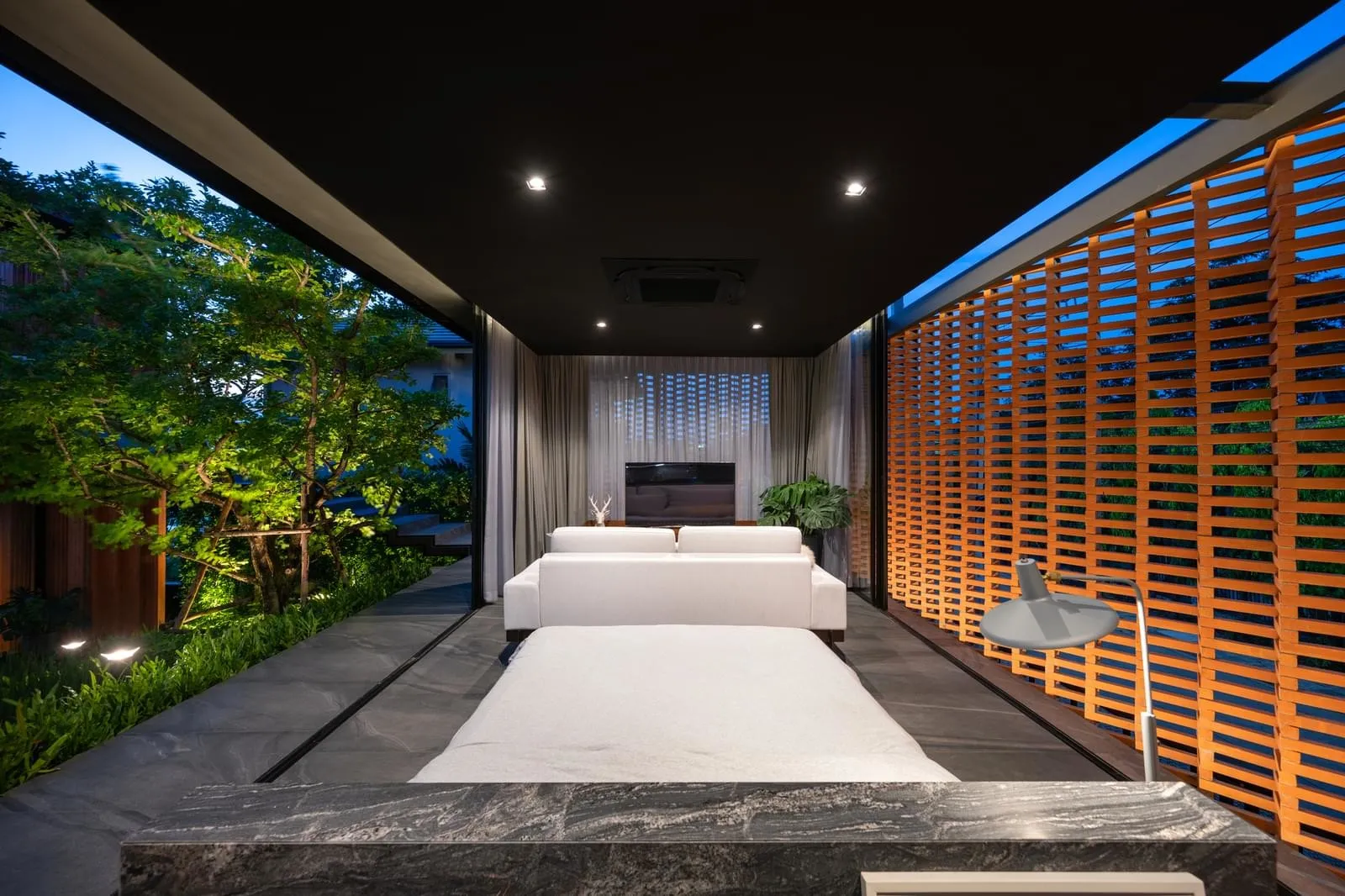 Modern minimalist living space with concrete floor, glass walls, and wooden elements.