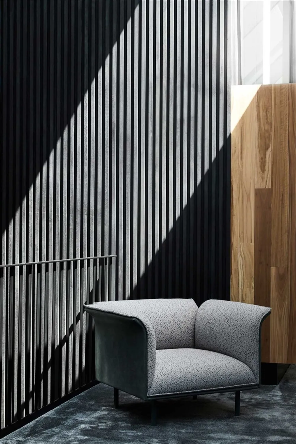 Modern office waiting area featuring wood paneling, metal railings, and upholstered seating.