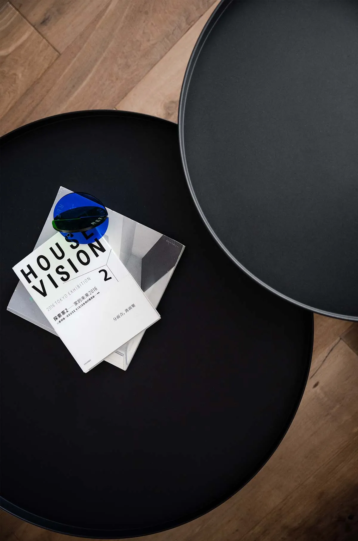 A sleek, modern black side table with a metallic finish, featuring a minimalist design and a blue circular object on top.