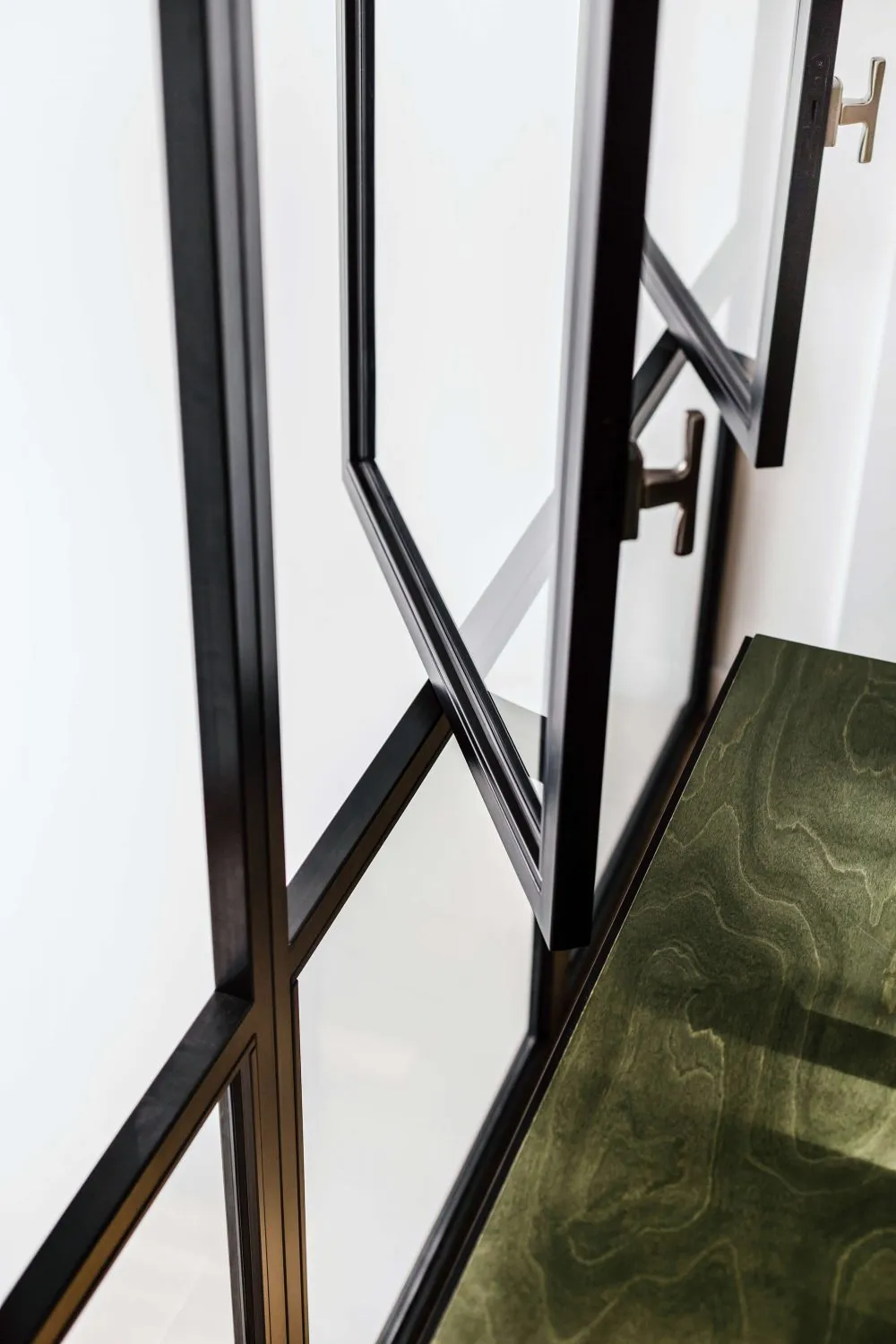 Modern interior design featuring black-framed glass doors and green marble surface.