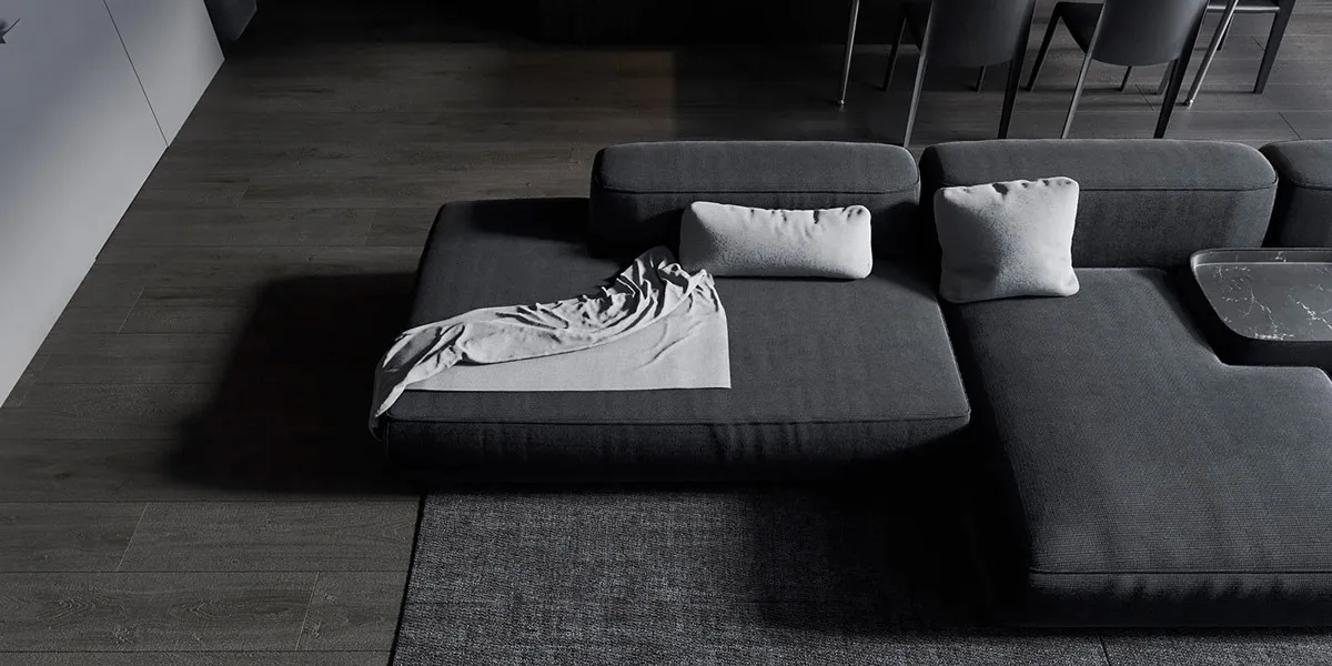 A modern living room featuring a grey fabric sectional couch with a blanket and pillows.