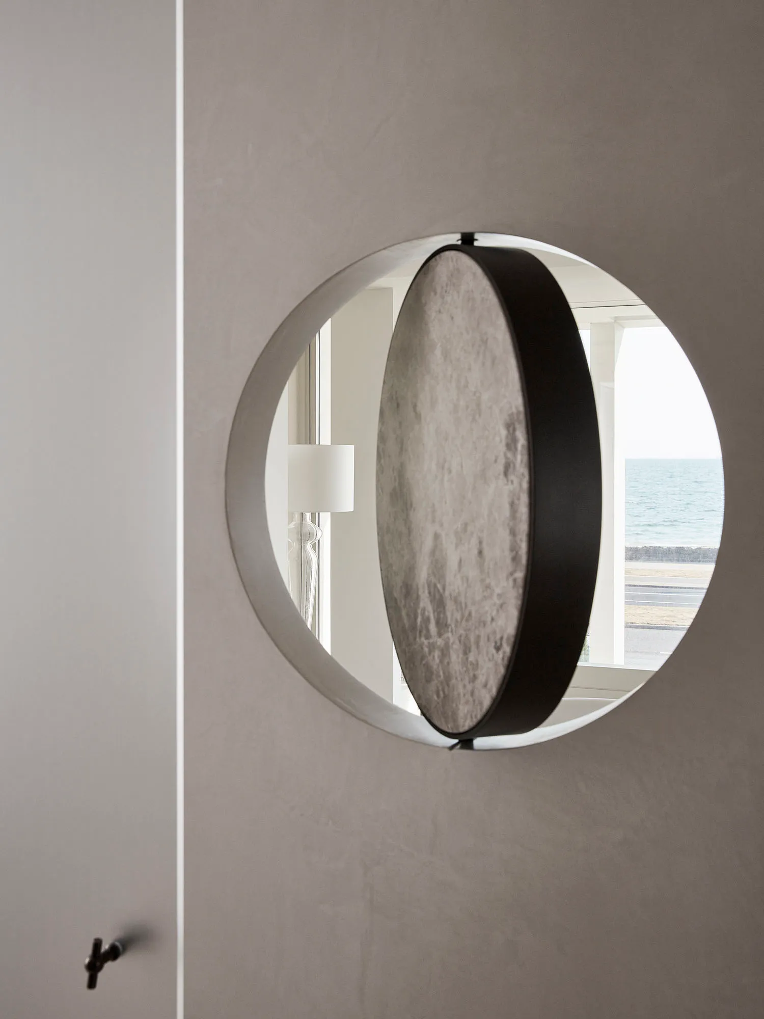 A modern decorative mirror with a metallic circular arc design mounted on a wall.