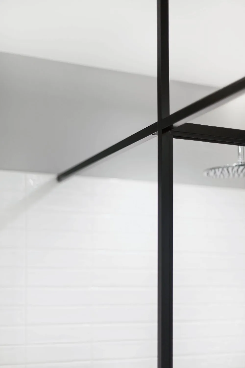 Modern minimalist bathroom featuring black metal frame, black glass shower enclosure, and white tiles.