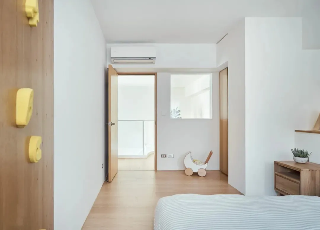 Minimalist bedroom with wooden furniture and a white air conditioner unit mounted on the wall.