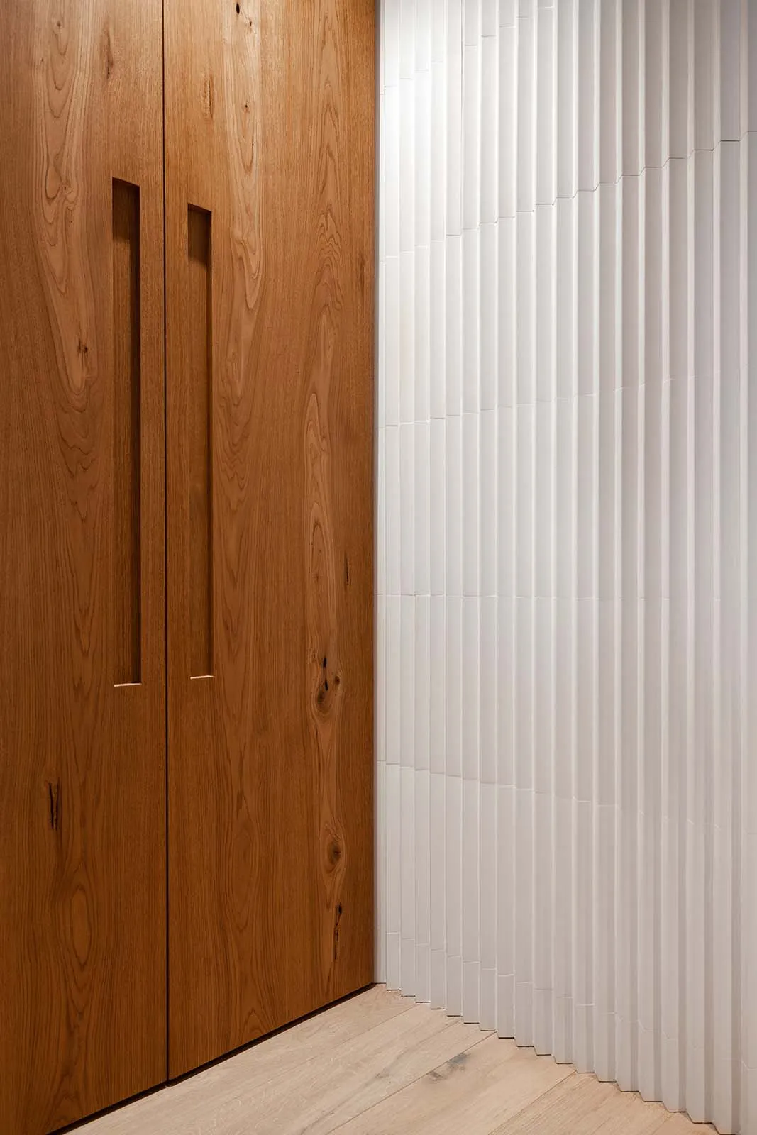 Modern wooden cabinets with vertical grain texture and light hardwood flooring.