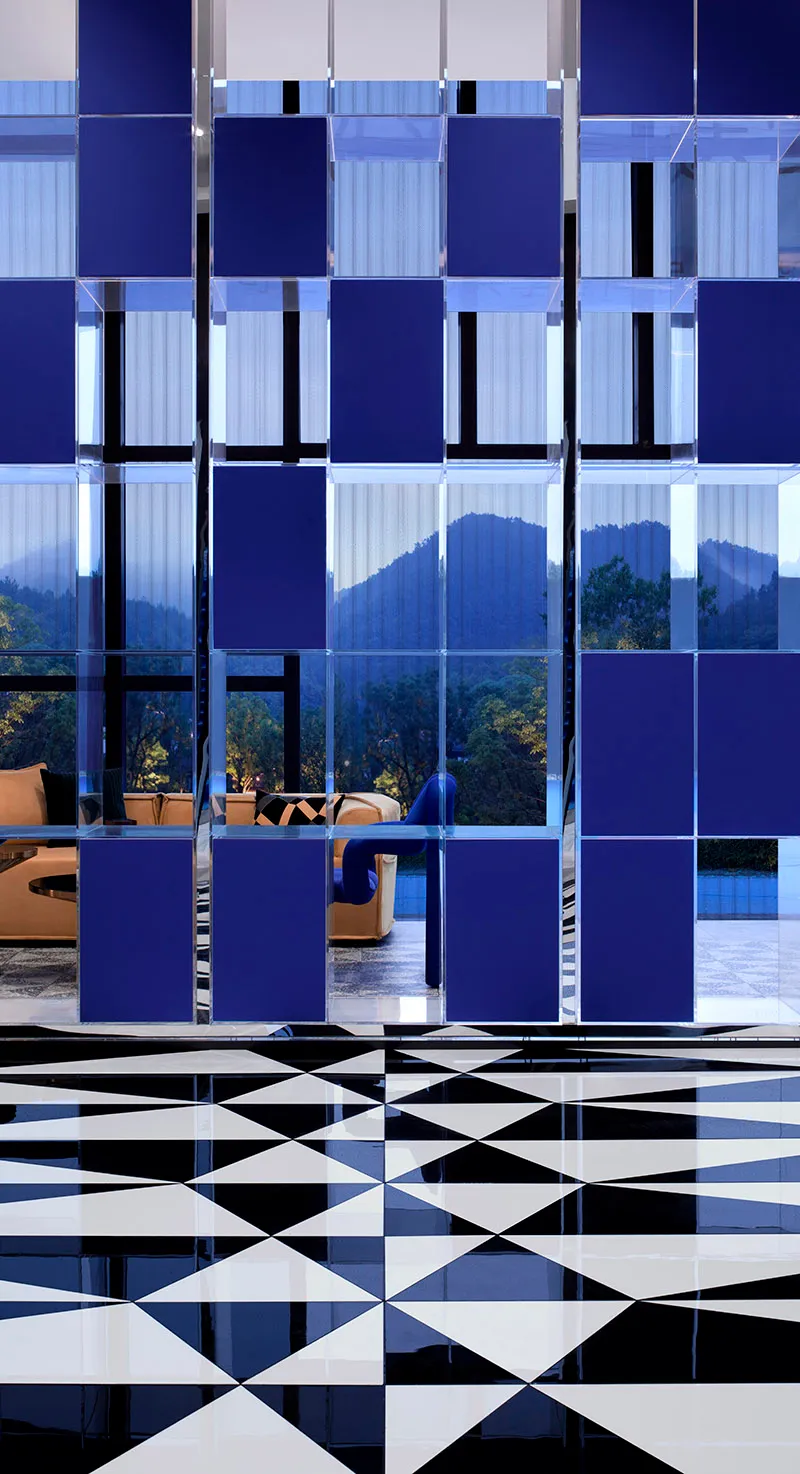 A modern living room with dark blue and white glass tiles on the floor and blue and white geometric patterns on the ceiling.