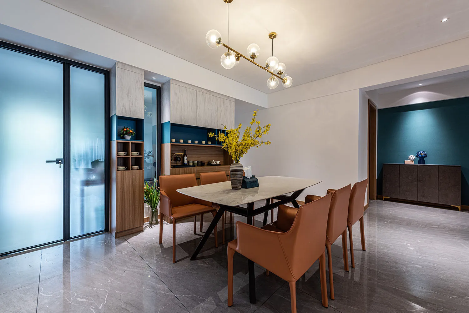 Modern dining room featuring a marble table and brown leather chairs.