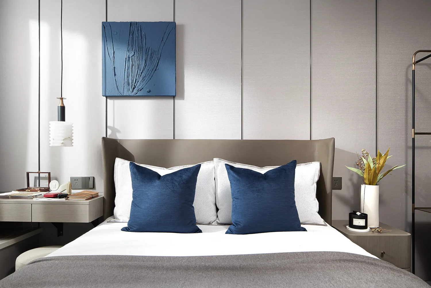 A modern classic bedroom featuring a bed with white and gray textiles, a wooden headboard, and a metal nightstand.