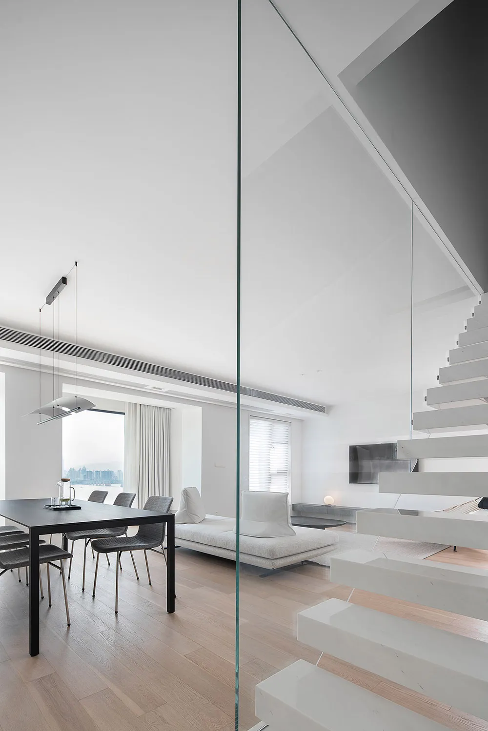 Modern minimalist living room featuring concrete flooring and glass elements.