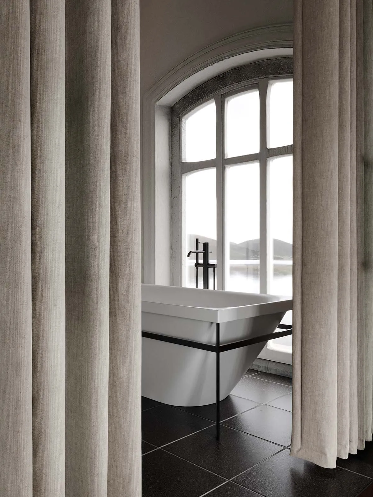 Modern minimalist bathroom featuring a ceramic bathtub with metal fixtures.