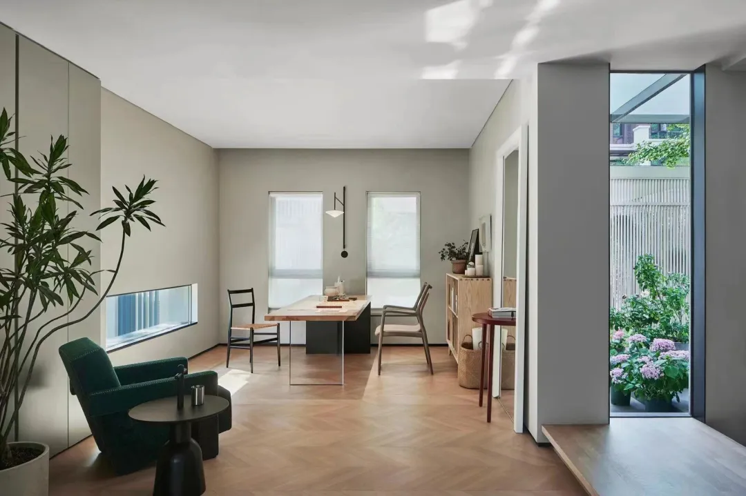 A minimalist residential space featuring wooden flooring, glass windows, and metal accents.