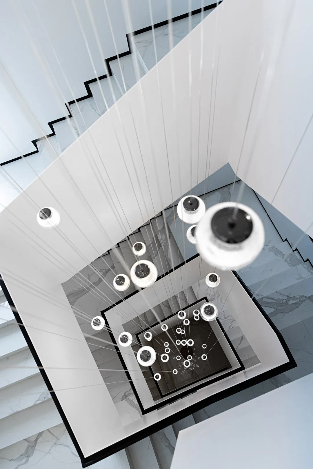 A minimalist modern interior featuring large glass light fixtures hanging from the ceiling.