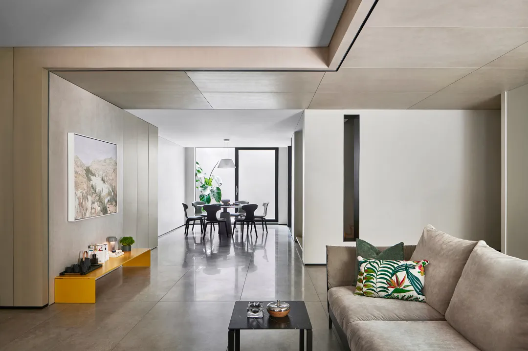 A modern living room with concrete walls and a glass partition.