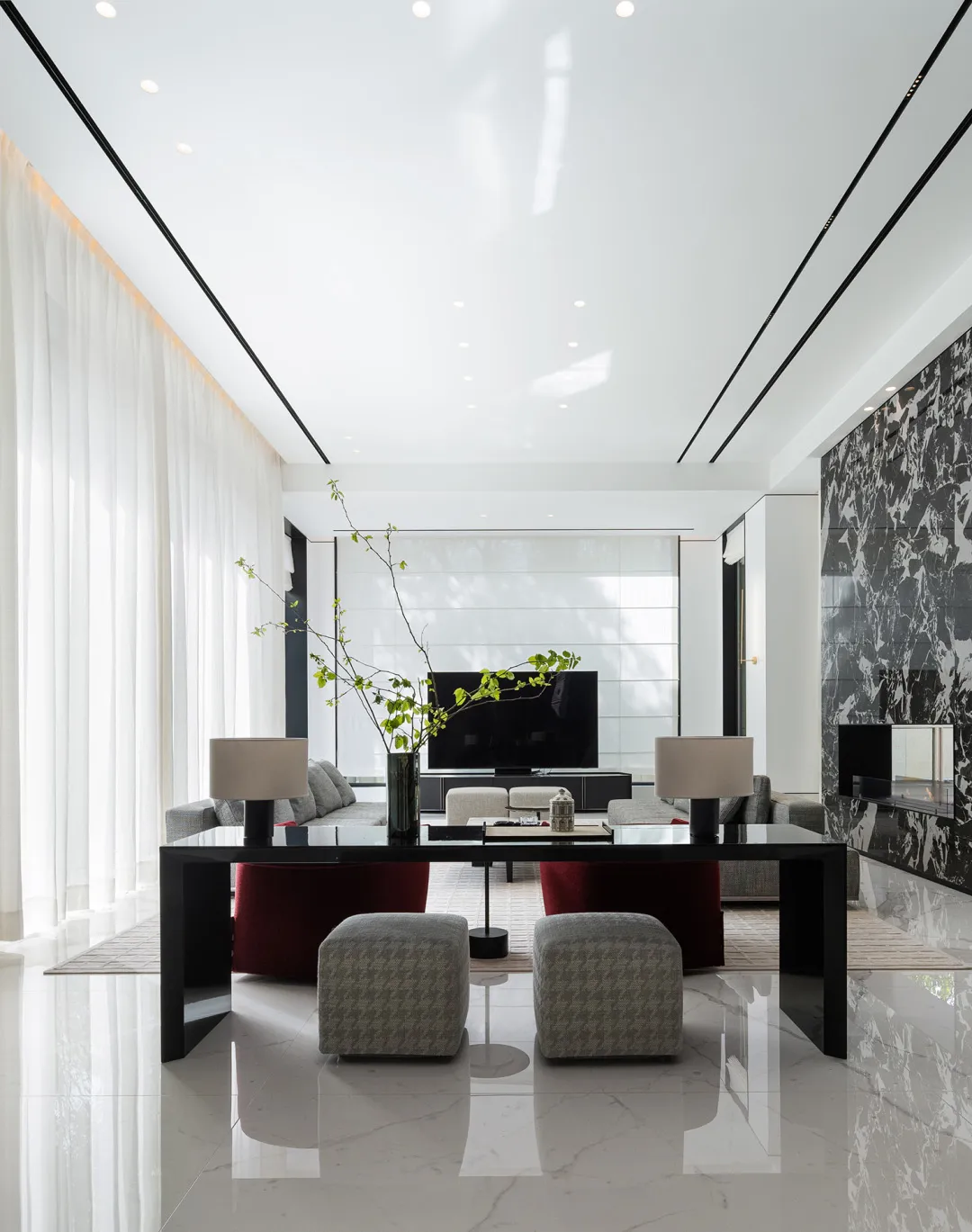 Modern living room featuring marble and glass materials with contemporary furniture and a large television.
