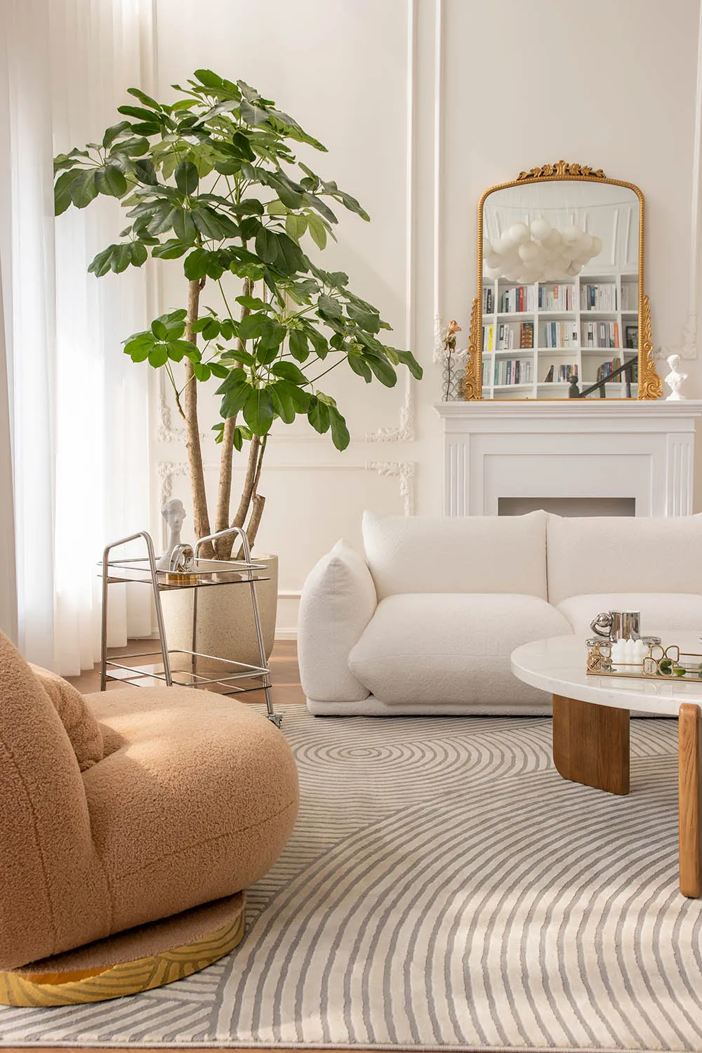 A modern living room decorated in neutral tones with a cozy sofa, round table, and large plant