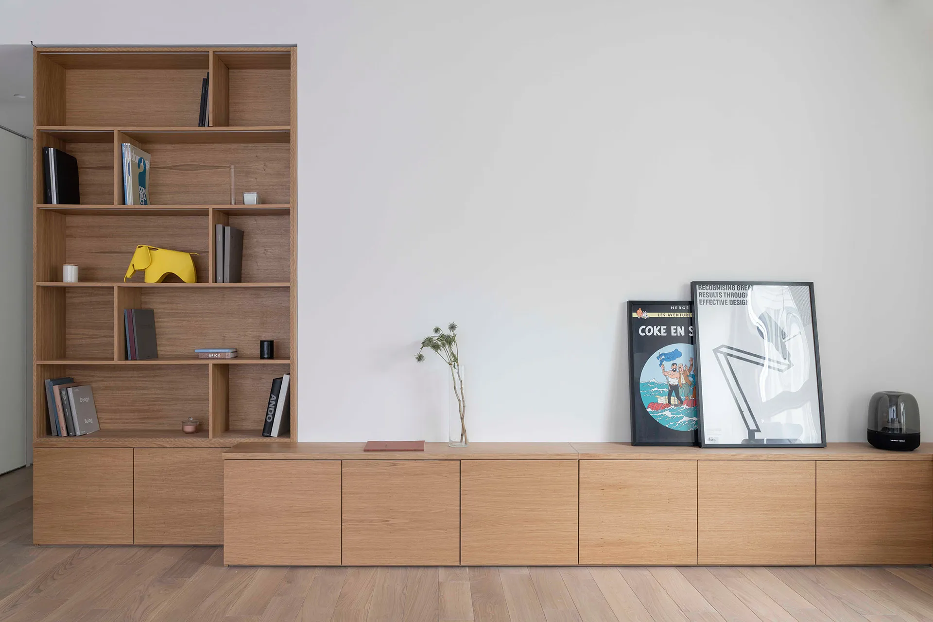 A modern minimalist interior featuring a wooden shelf with books and decorations.