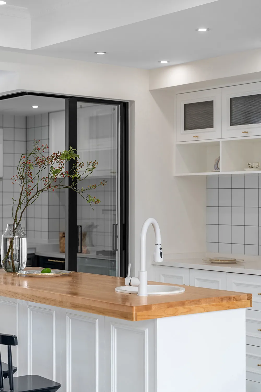 Modern minimalist kitchen featuring white cabinets and a wooden countertop.