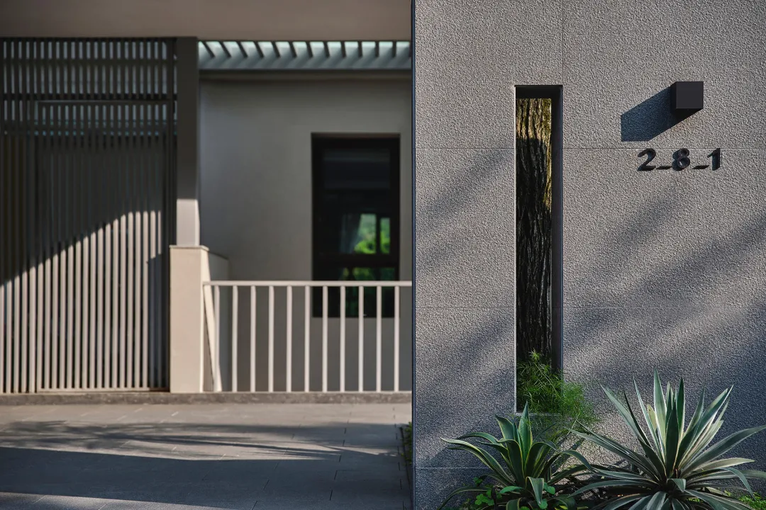 Modern building entrance with a concrete facade and a narrow vertical glass window.