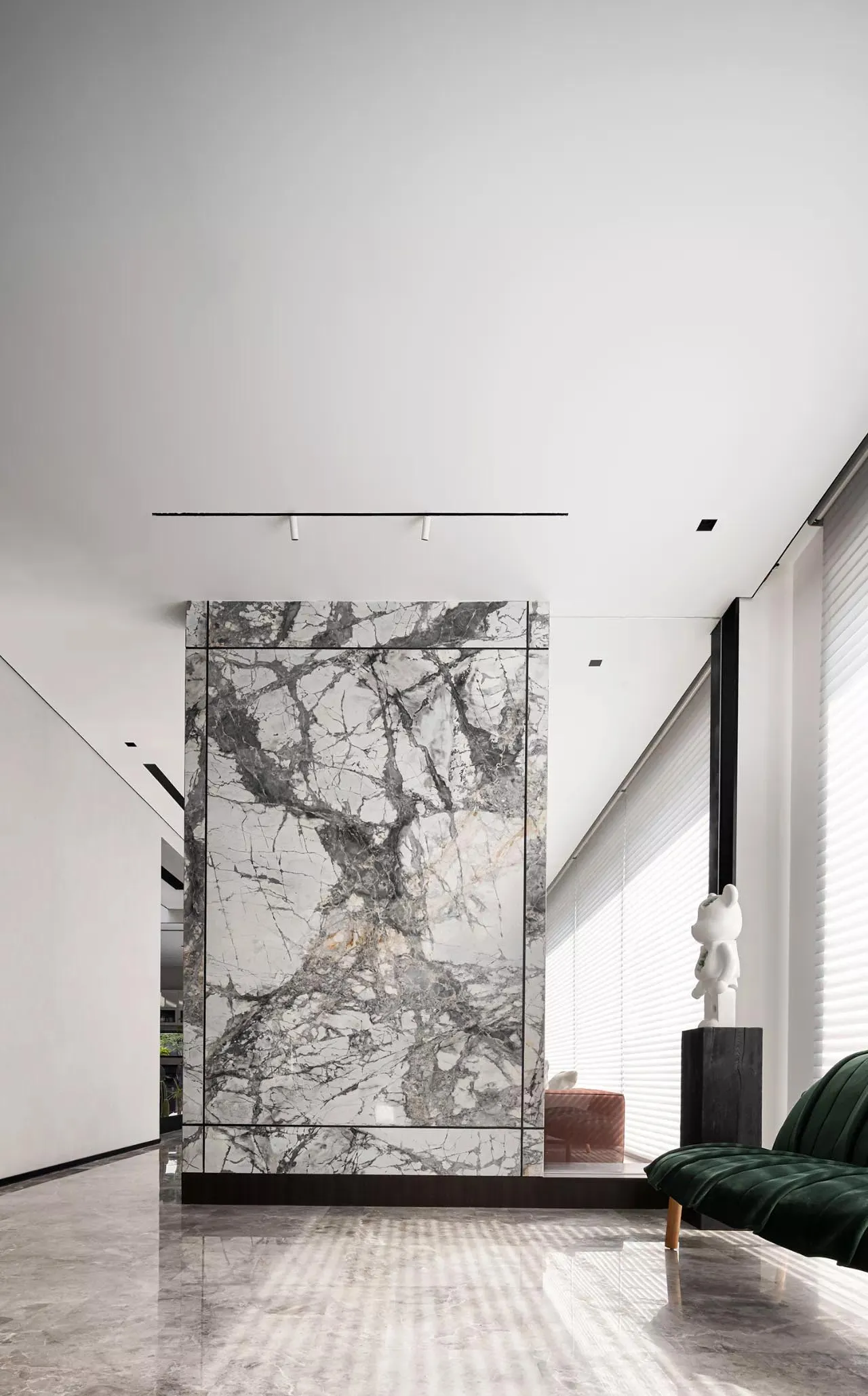 Modern living room featuring marble walls and floor, minimalist decor, and large windows.