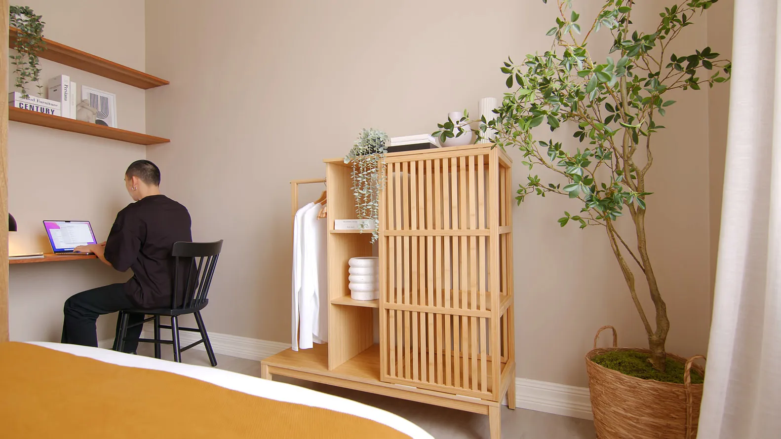 A minimalist small bedroom with wooden furniture and a green plant.