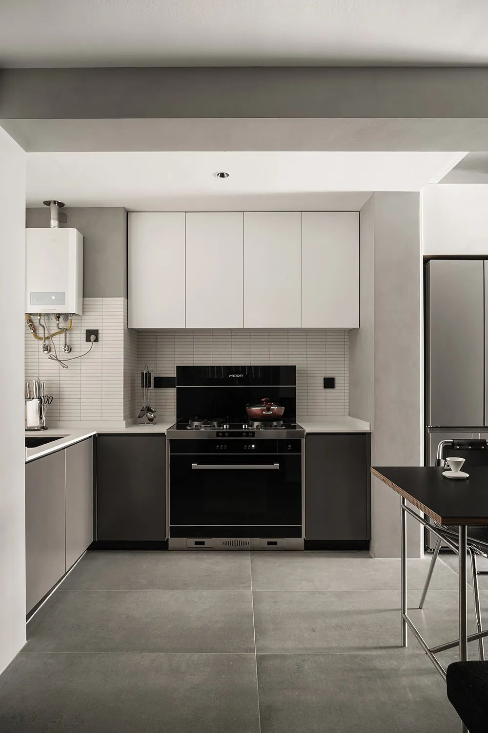 Modern kitchen with concrete flooring, minimalist design, white and black cabinets, and a black stove.