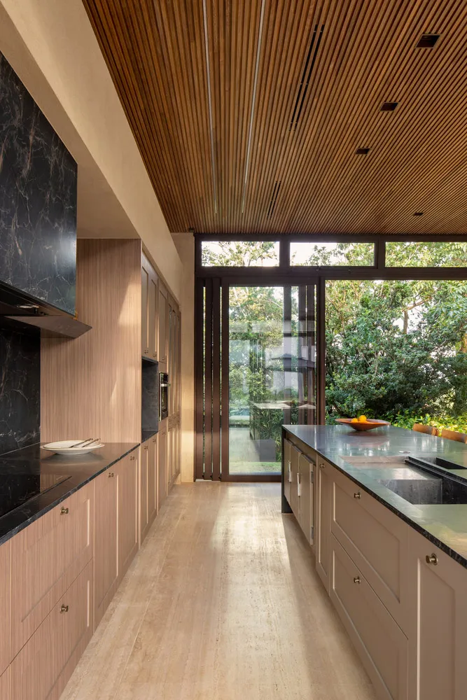A modern minimalist kitchen features sleek marble countertops and wooden cabinetry.