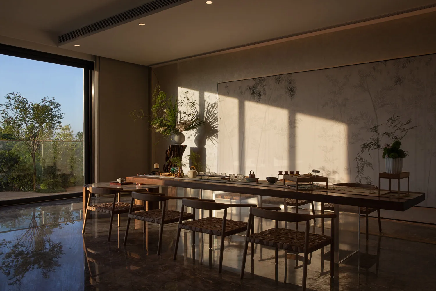 Modern dining room featuring wooden furniture, bamboo accents, and natural light casting shadows on the walls.