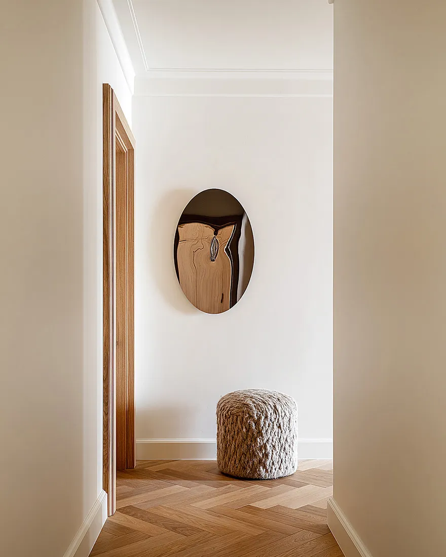 An entranceway featuring a minimalist design with wooden flooring and a textured pouf.